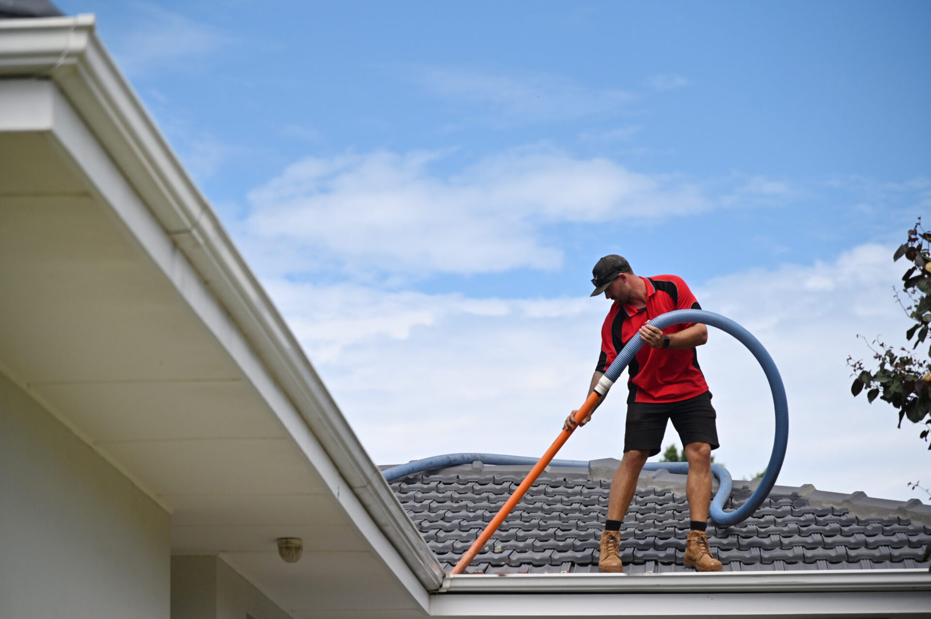 Professional young Gutter cleaner cleaning gutters working on house roof.