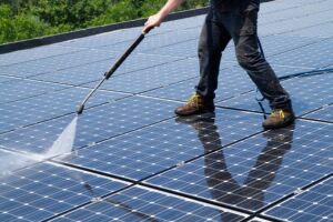 a guys cleaning solar panels on roof