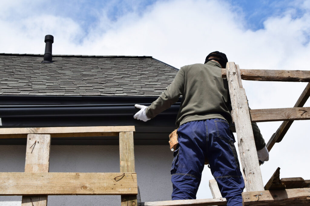 Man elevated in wood structure while installing gutter system