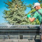 a man cleaning a gutter using water pressure